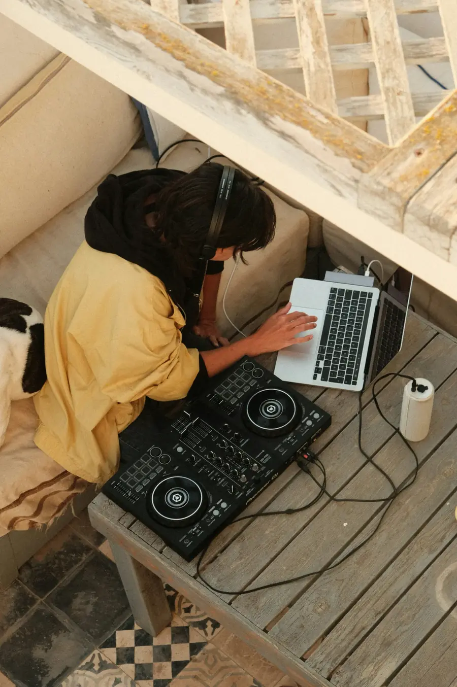 A DJ at the decks in warm orange light, a lamp glowing behind the mixer