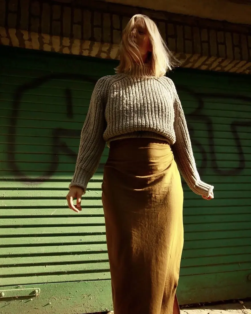 Mai standing in autumn sun in front of a green garage door
